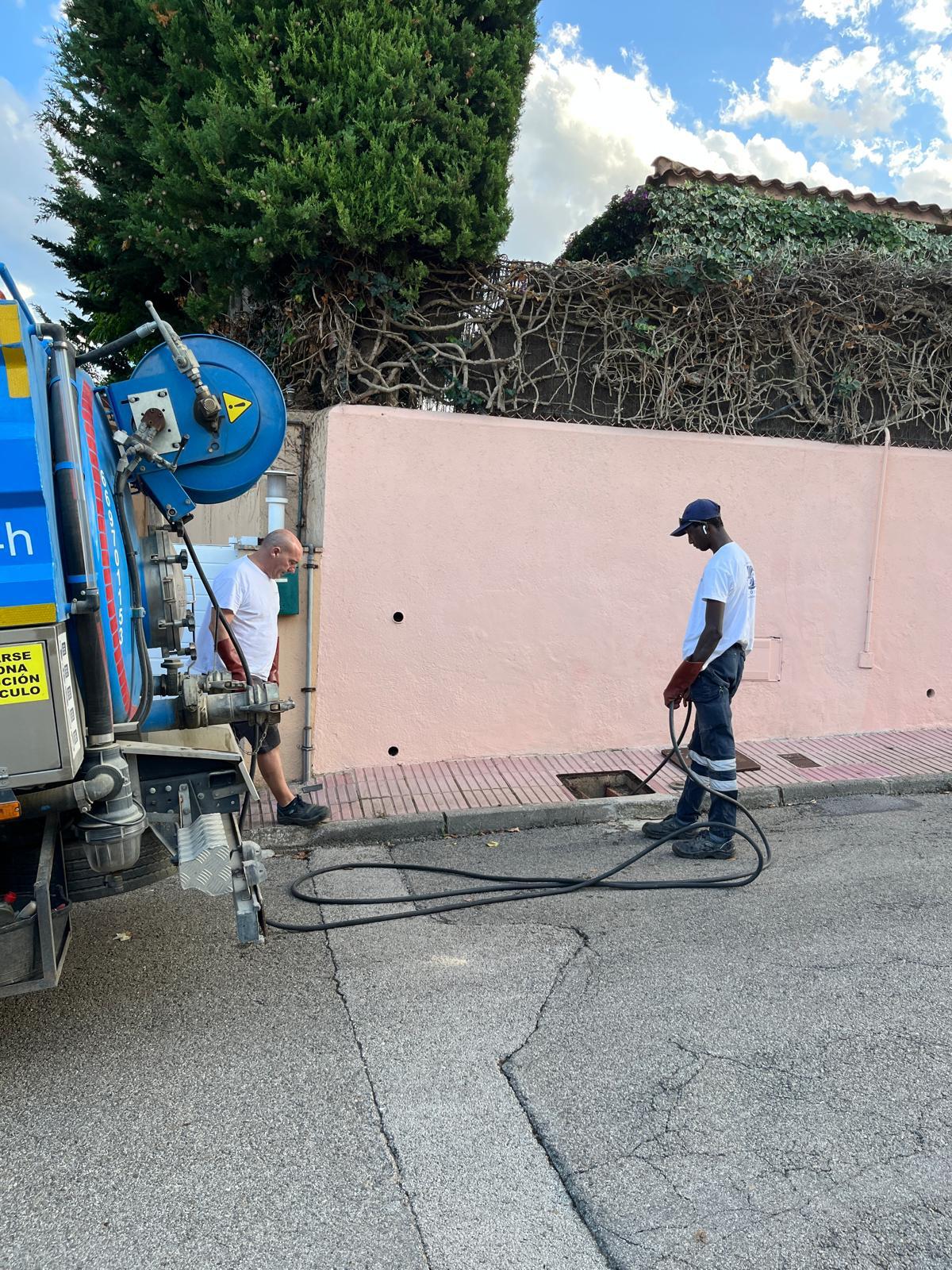 Operario realizando un desatasco con camión cuba en una calle, utilizando mangueras de alta presión.